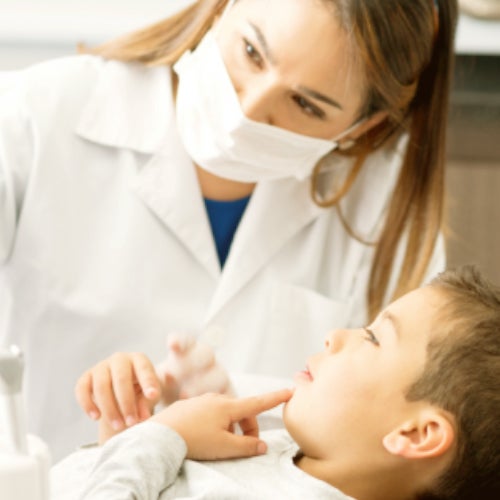 Zubařka kontroluje zuby mladému pacientovi.