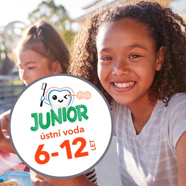 Usměvavá dívka venku vedle kulatého loga „Junior ústní voda 6–12 let“.